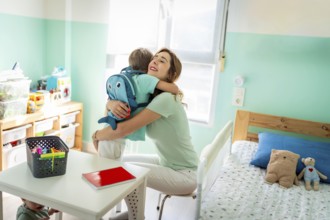 Tender mother embracing her son before going to school sitting on the kids bedroom