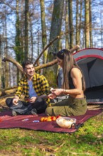 Hikers enjoying a game of cards while camping in the forest, sharing laughter and creating memories