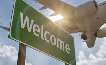 Welcome green road sign with airplane above