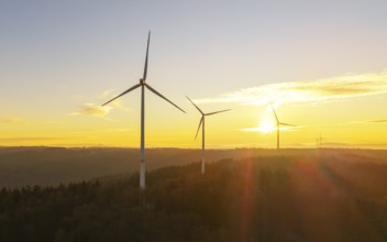 Wind turbines on hills at sunrise, natural landscape in orange and blue sky, wind farm, Rems