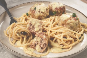 Spaghetti with chicken meatballs, with cream sauce, and parmesan cheese, and decorated with