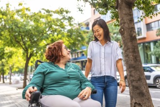 Asian woman and friend with disability talking and walking along a residential street