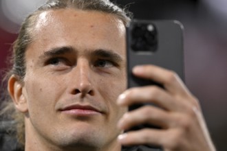 Tennis player Alexander Zverev visiting a Bundesliga match, portrait, takes selfie with smartphone,