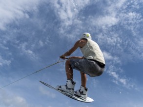 Young man jumping and flying with wakeboard, water sports and water skiing in the wakepark