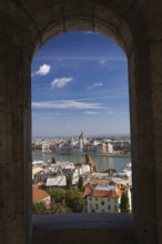 Budapest city skyline with Danube river and Hungarian parliament through stone arch in summer,