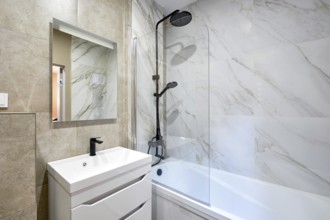 A beautifully designed bathroom showcases marble walls and a stylish shower-bathtub combo. A modern