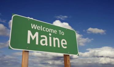 Welcome to maine green road sign over blue sky with some clouds