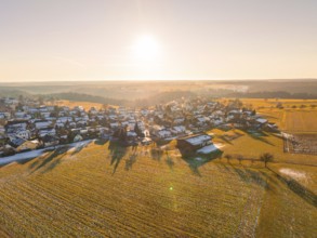 A snowy village in the light of the sunrise with surrounding fields, Neuweiler, district of Calw,