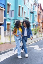 Vertical photo of a young african american couple walking together along a street with colorful