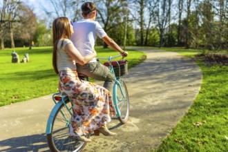 Romantic couple enjoying a leisurely bike ride through a sunny park, embracing the simple joys of