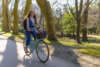 Young woman riding a vintage bicycle through a sunlit park, enjoying the fresh air and vibrant