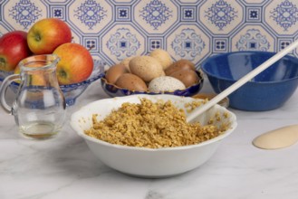 Oatmeal porridge with eggs and apples in a bowl on a marble worktop in front of patterned tiles
