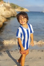 Happy child walking on the beach of s'amarador in mallorca, spain, enjoying summer holidays by the