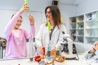 Female teacher assisting her student during a chemistry experiment in a school laboratory using
