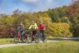 Three happy, active seniors ride their mountain bikes in the autumnal atmosphere of the autumn
