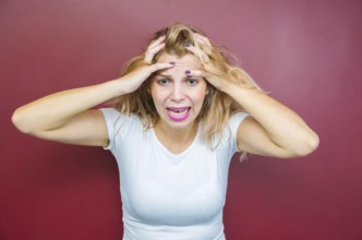 Concept of worry, woman with both hands on head on red background