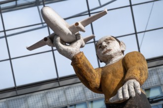 Sculpture, wooden figure with aeroplane at Munich Airport, Terminal 2, Munich, Bavaria, Germany,
