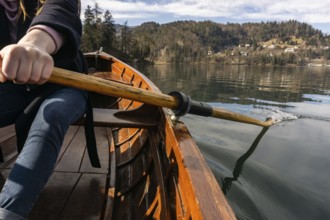 Young woman using paddle on a wooden boat, Lake Bled Slovenia rowing on wooden boats on a sunny day