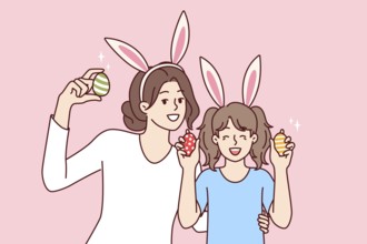 Easter eggs in hands of happy mother and daughter with bunny ears, to celebrate traditional