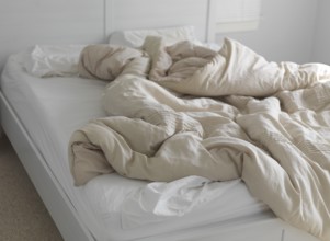 Unmade bed with ruffled blanket