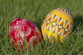 Two traditionally hand-painted Easter eggs lie in the grass
