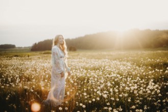 A woman in a field of flowers during sunset, surrounded by open space and golden light