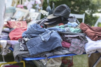 Used clothes and caps for sale at a flea market or garage market on a sunny weekend day, copy