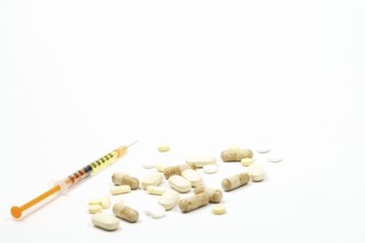 Syringe with vaccine next to a group of pills on white background and copy space