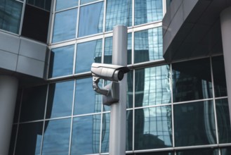 External surveillance camera against glass building facade