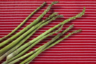 Green asparagus over red tablecloth background