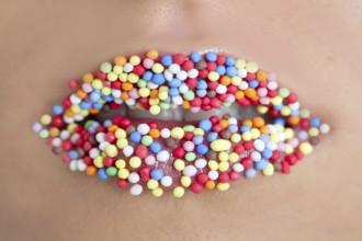 Close up of woman lips with multicolored sweet pearls