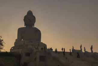 A picture of the large Phuket Big Buddha statue, at sunset, with tourists around