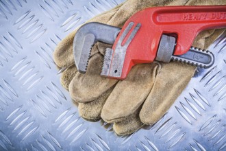 Leather protective gloves monkey wrench on corrugated metal background construction concept