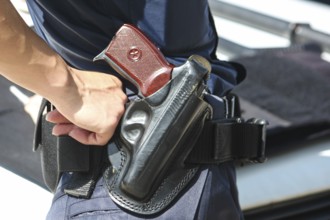 A woman's hand touches a body and a gun. Woman with a gun. Woman policemen with gun in a black
