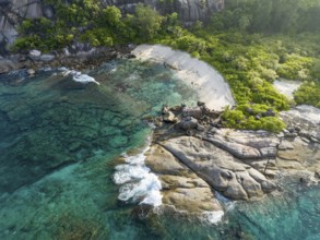 Coastline with waves, large rocks and tropical vegetation on turquoise water, aerial view,