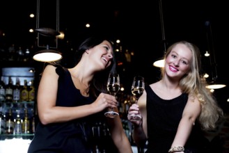 Two beautiful young women sharing their friendship and celebrating with champagne, in a fancy