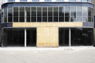 vacant commercial real estate with modern glass storefront boarded up after business closure