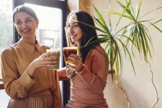 Happy young female friends having coffee break while relaxing at indoor cafe. Friendship concept