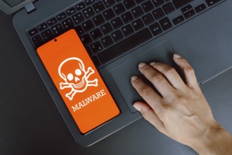 In this photo illustration, the Malware icon is displayed on a smartphone screen next to a person