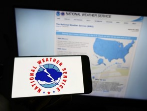 Stuttgart, Germany, 09-30-2022: Person holding cellphone with logo of US agency National Weather