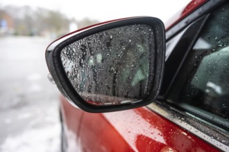 Fine water droplets on a side mirror of a red car