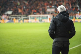Head coach's back and soccer match at the stadium in the background