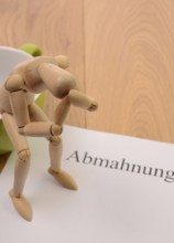 Letter of warning on a table, desperate figure sitting on a cup