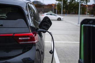 Black electric car charging at a parking lot