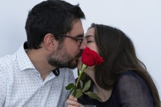 Young couple kissing with a red rose in front of them