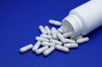 Large white pills fell from a large white bottle. Life without drugs and dependence on capsules of