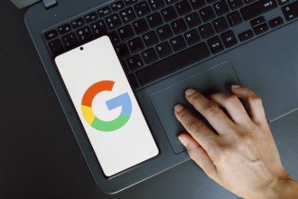 In this photo illustration, the Google logo is displayed on a smartphone screen next to a person