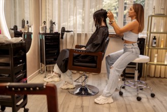 Professional female hairdresser cuts hair of woman while working in beauty salon