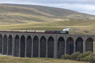 Steam train crossing Ribblehead Viaduct, railway bridge over the valley of the River Ribble at the