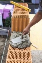 Anonymous construction worker on a building site erecting a brick wall. Brick wall of a solid house